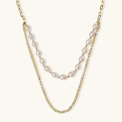 Layered gold chain necklace with organic baroque freshwater pearls and adjustable length on cream background